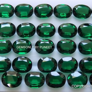 May include: A collection of 40 oval-shaped, green gemstones. The gemstones are arranged in four rows of ten, on a white surface. The text "GEMSONLY BY PUNEET" and "COPYRIGHT PROTECTED - GEMSONLY" are visible in the image.