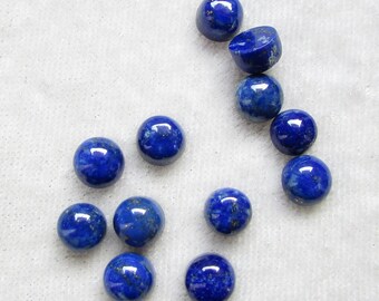 May include: A collection of ten round, blue lapis lazuli cabochons. The cabochons are smooth and polished, with a deep blue color and flecks of gold pyrite.