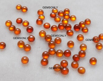 May include: A collection of 30 round, orange-brown gemstone cabochons. The cabochons are approximately 4mm in diameter and have a smooth, polished surface. GEMSONLY is printed on the white background.