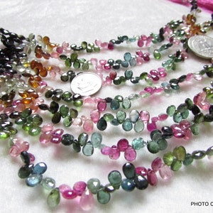 May include: A strand of multi-colored gemstone beads, including pink, green, blue, and brown, in a teardrop shape. The beads are strung on a thin cord and are approximately 5mm in size.