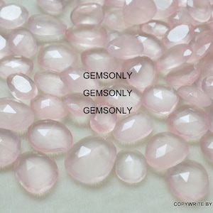 Pu&ograve; includere: Una collezione di pietre preziose di quarzo rosa rosa pallido, ciascuna con una forma ovale sfaccettata. Le pietre sono lisce e traslucide, con un leggero luccichio.