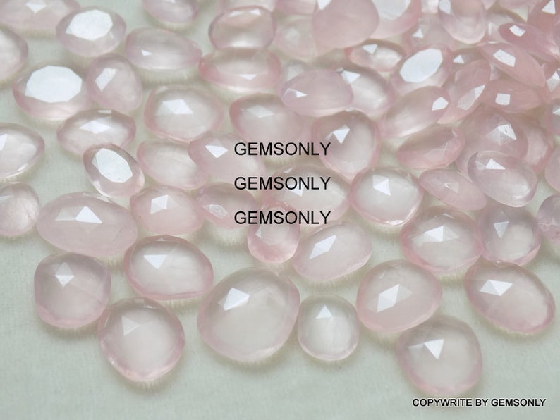 Pu&ograve; includere: Una collezione di pietre preziose di quarzo rosa rosa pallido, ciascuna con una forma ovale sfaccettata. Le pietre sono lisce e traslucide, con un leggero luccichio.