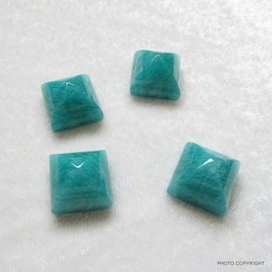 May include: Four square-shaped, teal green amazonite gemstones. The gemstones are faceted and have a smooth, polished finish.