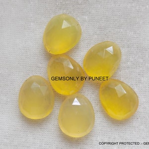 Puede incluir: Seis cabujones de piedra preciosa amarilla con bordes facetados. Las piedras son de forma ovalada y tienen una apariencia translúcida.
