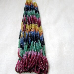 May include: A strand of colorful gemstone beads, including red, pink, green, blue, and yellow. The beads are strung on a white thread and are ready to be used for jewelry making.