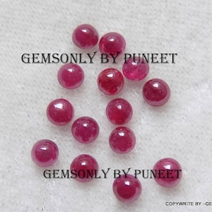 Puede incluir: Una colección de 12 piedras preciosas redondas de color rojo. Las piedras preciosas están sueltas y dispersas sobre una superficie blanca. El texto "GEMSONLY BY PUNEET" aparece dos veces en la imagen.