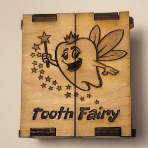 May include: A wooden box with a hinged lid, decorated with a cartoon tooth fairy holding a wand and surrounded by stars. The box is labeled "Tooth Fairy".