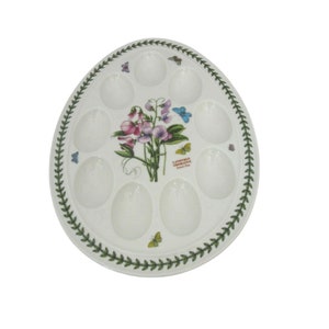 May include: White ceramic egg plate with 10 individual egg-shaped indentations. The plate features a green border with a floral design and the text "Lathyrus Odoratus Sweet Pea".
