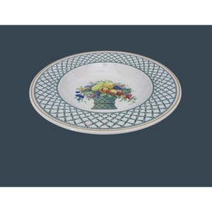 May include: A white ceramic plate with a green lattice pattern around the rim and a gold trim. The center of the plate features a basket of colorful fruit, including apples, pears, and grapes. This decorative plate is suitable for serving food.