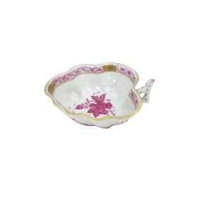 May include: A white, leaf-shaped porcelain dish with a pink floral design in the center. The rim is trimmed with gold and pink accents. A small handle extends from the side. This decorative dish is ideal for serving small portions.