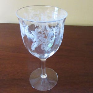 May include: A clear glass wine glass with an etched floral design.