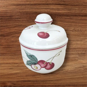 May include: White ceramic sugar bowl with a red lid and cherry design. The bowl has a red rim and a cherry design on the front.
