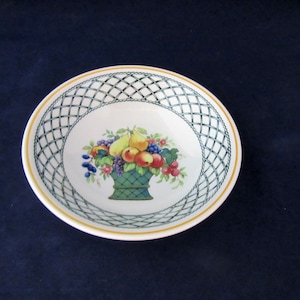 May include: White ceramic bowl with a fruit basket design. The bowl features a green lattice pattern around the rim and a yellow border. The center of the bowl displays a colorful illustration of a basket filled with various fruits.