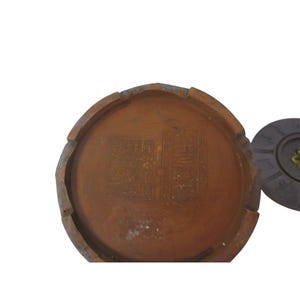 May include: A brown, round, antique container with carved text. The container has a dark brown lid with a gold-colored accent. The container's interior has carved text. The container is set against a white background.