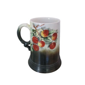 May include: A white ceramic mug with a green and white cherry design. The mug has a handle and a wide base.