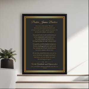 Op de afbeelding: Ingelijste zwart-gouden print met tekst ter ere van dominee James Barlow. De tekst is in een gouden scriptlettertype op een donkere achtergrond, omlijst met een gouden rand. De print bevat de Fellowship Church Woodland Hills 2025.