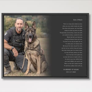 May include: A framed photograph features a man in a police uniform kneeling next to a German Shepherd dog. The photo includes text that reads "End of Watch" and a poem, with the text "In Memory of Kojak EOW 12-7-2025".