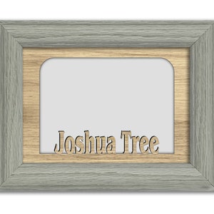 May include: A gray wood picture frame with a natural wood inner frame. The words "Joshua Tree" are cut out of the inner frame.