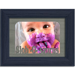 May include: A framed photo of a baby with purple paint on their face and hands. The photo is in a blue frame with a gray mat. The text "Slob-O-saurus" is printed below the photo.