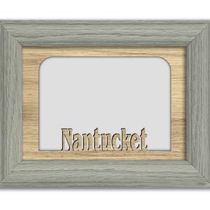 May include: A gray wood picture frame with a light brown wood mat and the word "Nantucket" cut out of the mat.