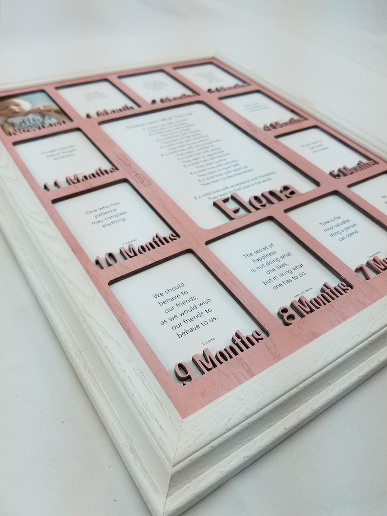 May include: A pink and white wooden photo frame with 12 openings for pictures. The frame has a pink background with white lettering that says "1 Month", "2 Months", "3 Months", "4 Months", "5 Months", "6 Months", "7 Months", "8 Months", "9 Months", "10 Months", "11 Months", and "12 Months". The frame also has a quote in each opening. The quote in the 9 month opening says "We should behave to our friends, as we would wish our friends to behave to us."