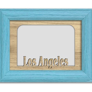 May include: A light blue picture frame with a wood-toned inner frame. The word "Los Angeles" is cut out of the inner frame.