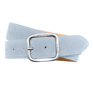 May include: A light blue suede belt featuring a rectangular silver-toned metal buckle with a distressed finish. The belt strap has a soft, matte texture and includes several punched holes for adjustment, with a tan-colored interior lining visible.