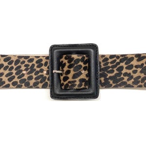 Op de afbeelding: Een bruine en zwarte riem met luipaardprint en een grote zwarte vierkante gesp.