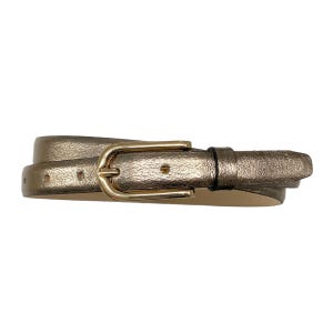 Könnte beinhalten: Ein schmaler Gürtel mit metallisch bronzefarbenem Finish und glatter Textur. Der Gürtel verfügt über eine glänzende goldfarbene Metallschnalle mit abgerundetem rechteckigem Rahmen und Dorn sowie eine passende Metallschlaufe und vorgestanzte Löcher.