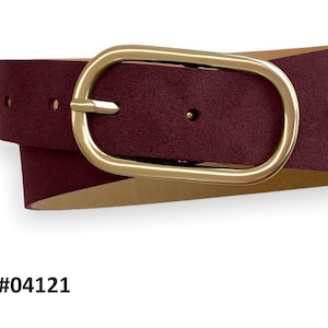 May include: A burgundy belt with a matte texture and a smooth, oval-shaped gold-tone metal buckle. The belt features a series of adjustment holes and is labeled with the text Col. #04121. The strap has a light-colored interior lining.