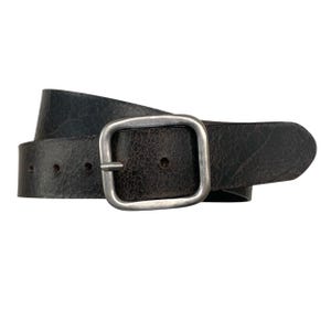 Puede incluir: Un cinturón de cuero marrón oscuro con una hebilla plateada. El cinturón tiene un aspecto desgastado y está hecho de cuero texturizado.