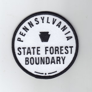 Könnte beinhalten: Ein weißer runder Aufnäher mit schwarzem Text und schwarzem Rand. Der Text lautet "Pennsylvania State Forest Boundary" mit einem stilisierten Bild des Bundesstaates Pennsylvania in einem Kreis.
