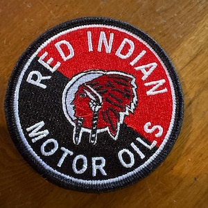 Puede incluir: Parche redondo bordado con las palabras "RED INDIAN MOTOR OILS" en letras blancas. Presenta un perfil de nativo americano en rojo y blanco sobre un fondo rojo y negro.