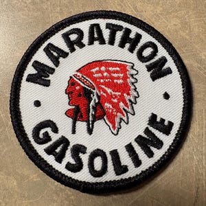 May include: Round patch with a white background, black border, and the words "MARATHON GASOLINE" in black. The patch features a Native American profile in red and black.
