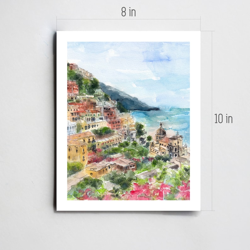 May include: Watercolor painting of a colorful Italian village on a hillside overlooking the ocean. The painting features a church with a dome, a beach, and a blue sky with white clouds. The painting is 10 inches tall and 8 inches wide.