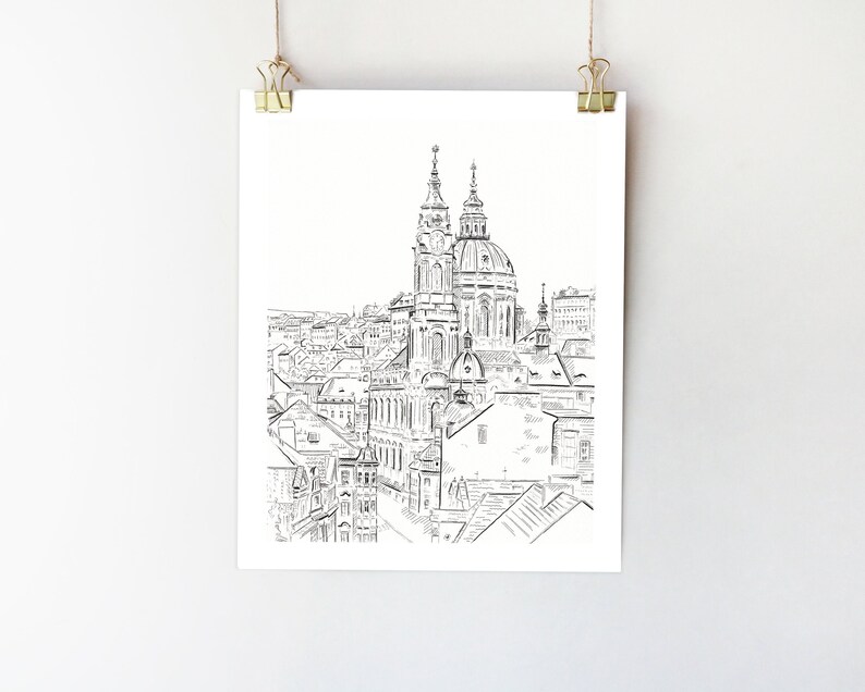 May include: A black and white line drawing of a cityscape with a prominent church in the center. The church has two towers and a dome. The drawing is done in a simple style, with minimal detail.