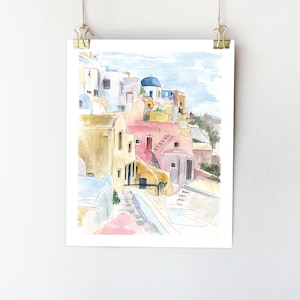 May include: Watercolor painting of a colorful village with whitewashed buildings, blue domes, and a winding staircase. The buildings are painted in shades of yellow, pink, and blue, and the sky is a soft blue.