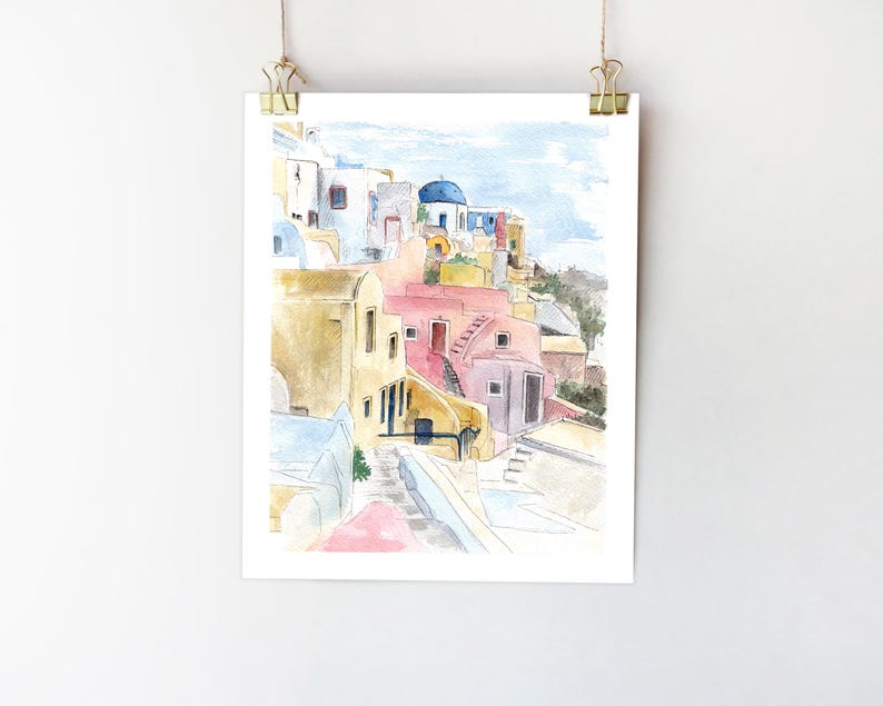 May include: Watercolor painting of a colorful village with whitewashed buildings, blue domes, and a winding staircase. The buildings are painted in shades of yellow, pink, and blue, and the sky is a soft blue.