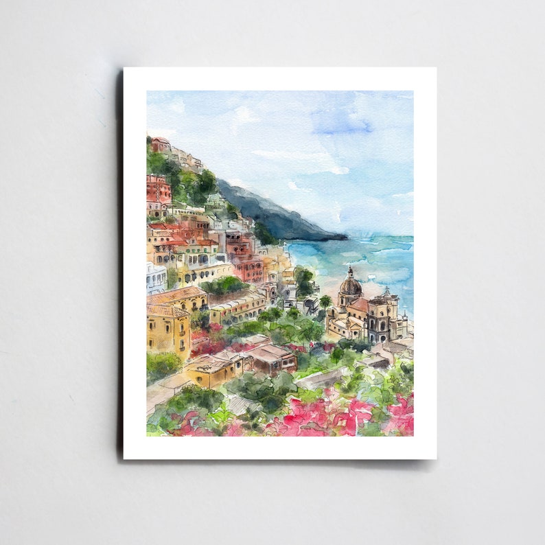 May include: Watercolor painting of a colorful Italian village on a hillside overlooking a blue ocean. The village is made up of many buildings with red tile roofs and white walls. There are trees and flowers in the foreground.