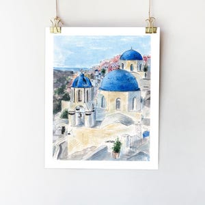 May include: Watercolor painting of a white building with blue domed roofs in a village setting. The building has a bell tower and is surrounded by other buildings.