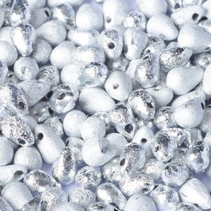 May include: A large quantity of silver teardrop-shaped beads. The beads have a textured, frosted finish.