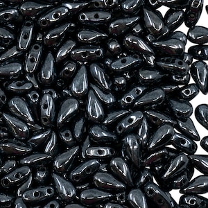 May include: A large pile of black teardrop-shaped glass beads. The beads have a shiny, metallic finish.