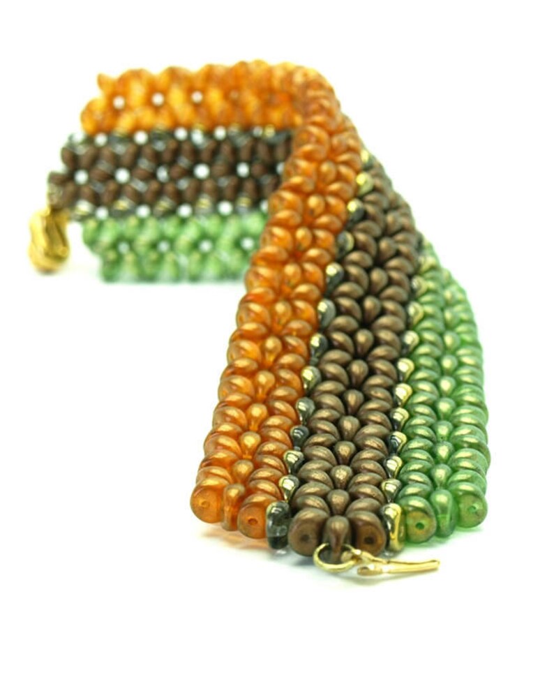 May include: A multi-coloured beaded bracelet featuring orange, brown and green beads. The bracelet is crafted from small, round beads woven together in a pattern.