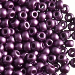 May include: A close-up of a pile of small, round, purple beads. The beads have a shiny, metallic finish.