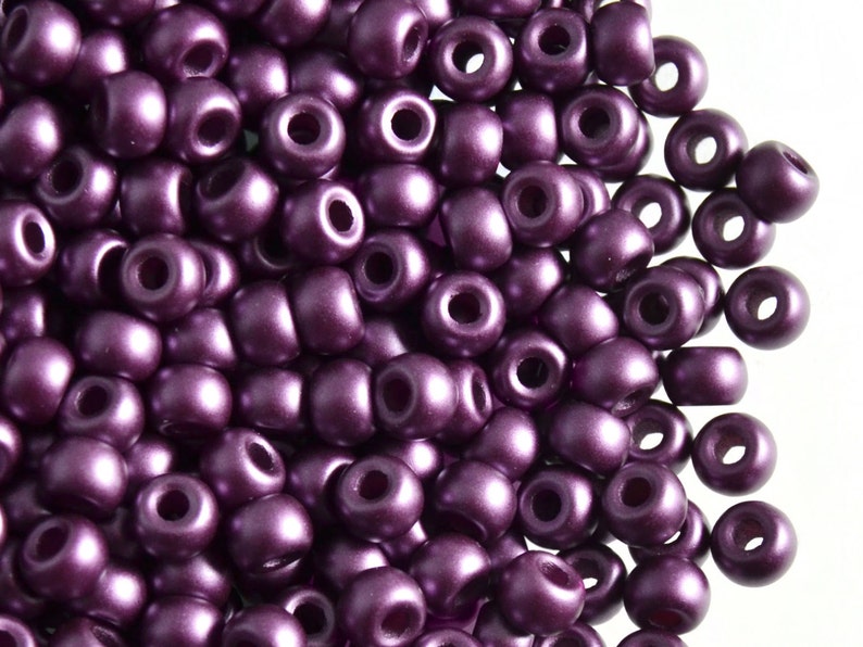 May include: A close-up of a pile of small, round, purple beads. The beads have a shiny, metallic finish.
