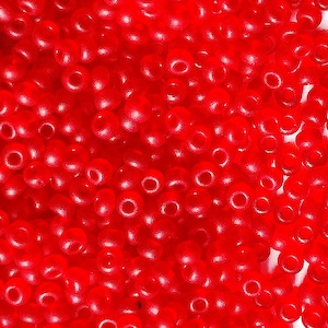Pode incluir: Uma imagem de close-up de uma grande quantidade de pequenas contas redondas vermelhas. As contas são opacas e têm um brilho ligeiro.