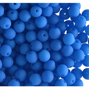 May include: A large pile of small, round, matte blue beads. The beads are all the same size and shape, and they are arranged in a random pattern.