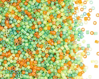 May include: A large pile of small, colorful glass beads in shades of green, yellow, and orange. The beads are round and have a hole in the center. They are scattered on a white background.