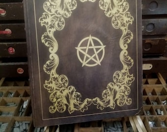 May include: A dark brown leather-bound journal with a gold pentagram design and ornate gold scrollwork on the cover.