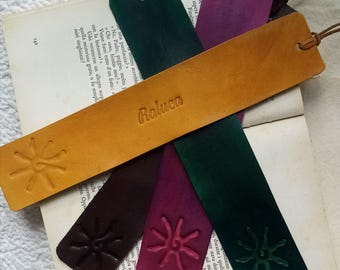 May include: Five leather bookmarks with a star design and the name "Raluca" embossed on one bookmark. The bookmarks are in shades of brown, purple, green, and dark green.